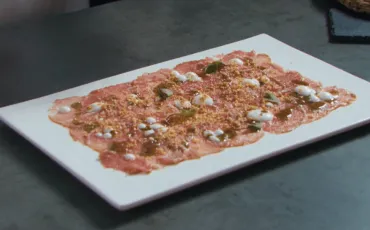 Receta de carpaccio de presa macerada con salsa de yogur, albahaca y maíz.